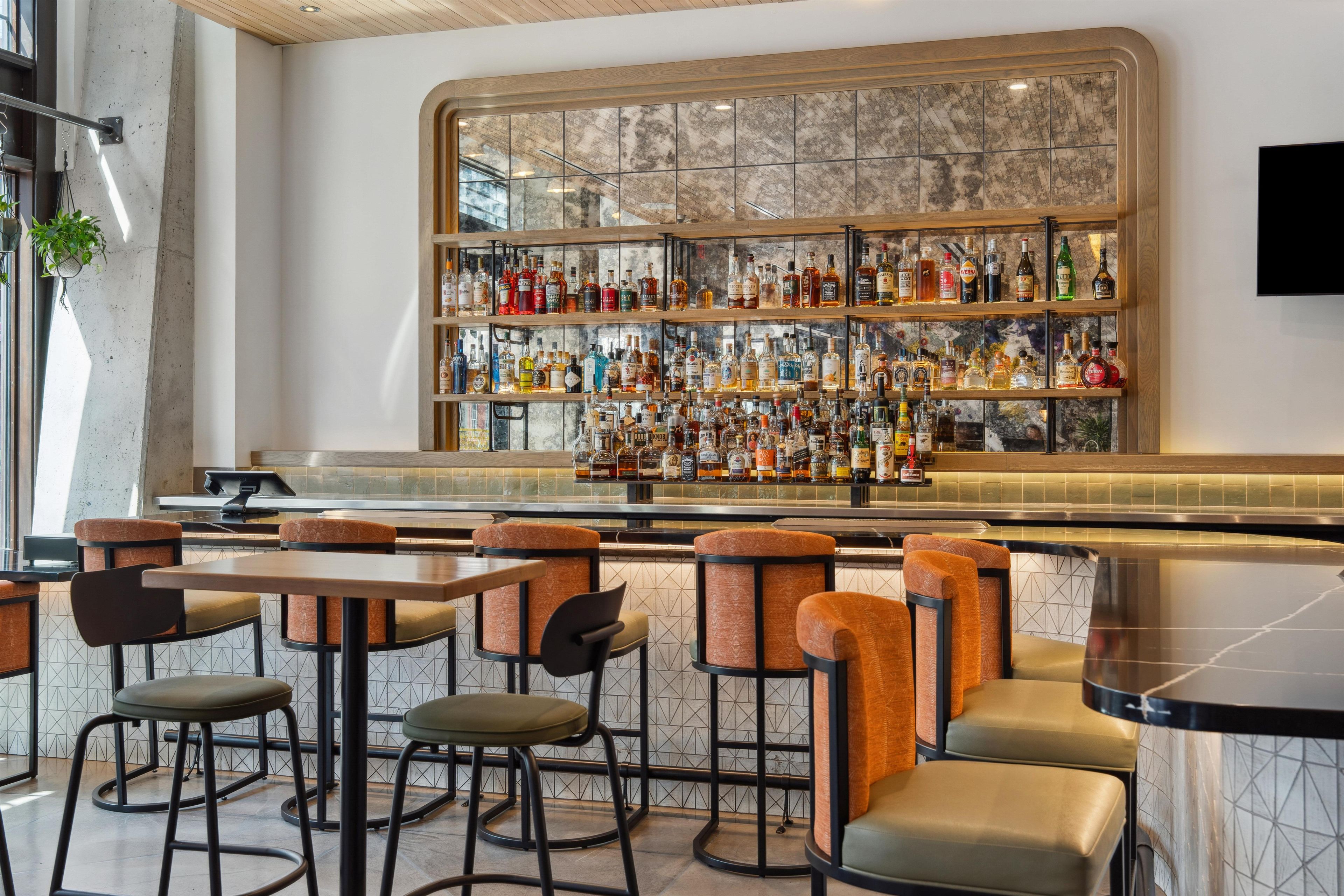 A bar area with multiple seating options and a variety of liquor bottles on shelves.