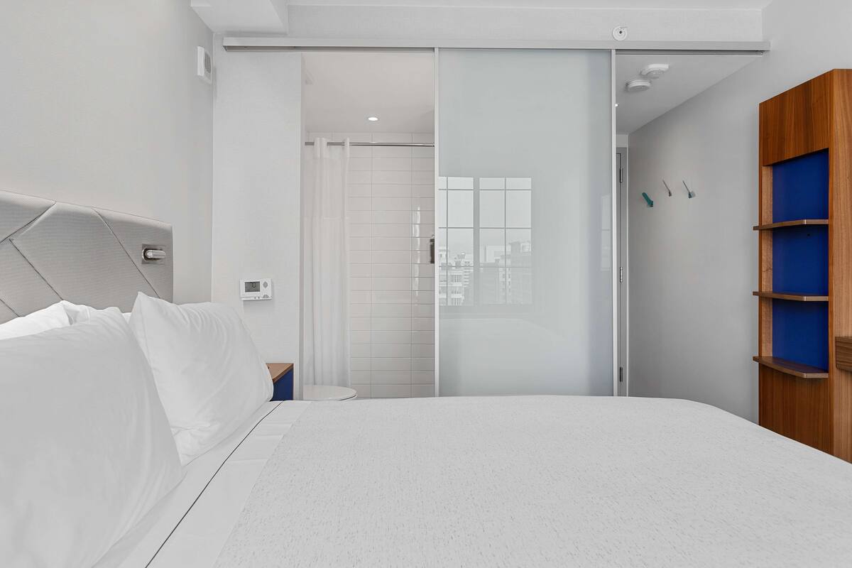 Ein modernes Schlafzimmer mit einem Bett, einer Schiebetür, einem Holzschrank und einem kleinen Nachttisch.
