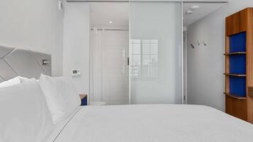 Un dormitorio moderno con una cama, una puerta corredera, un armario de madera y una mesita de noche pequeña.