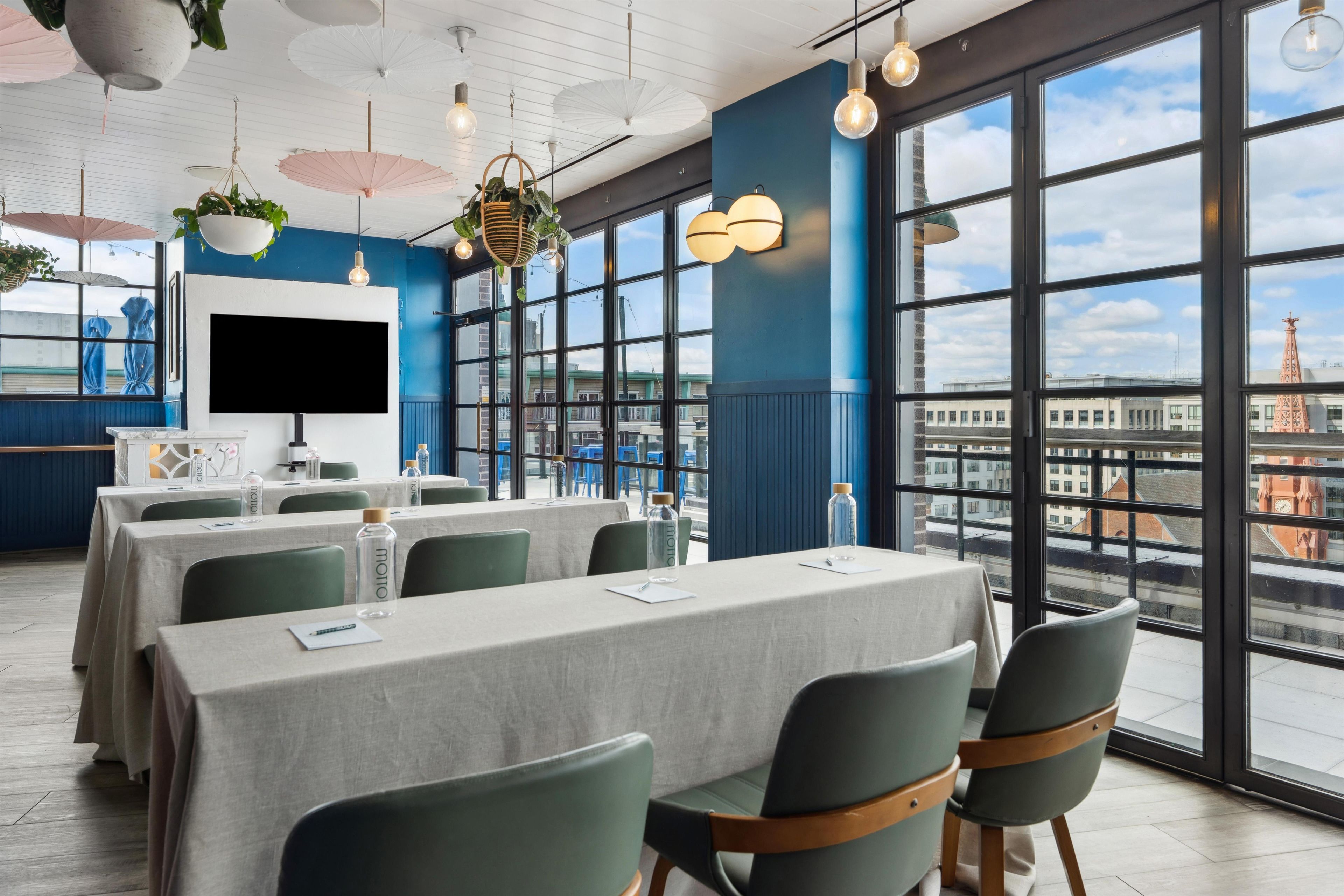 Une salle de conférence équipée de tables, de chaises et d’une grande fenêtre donnant sur la ville.