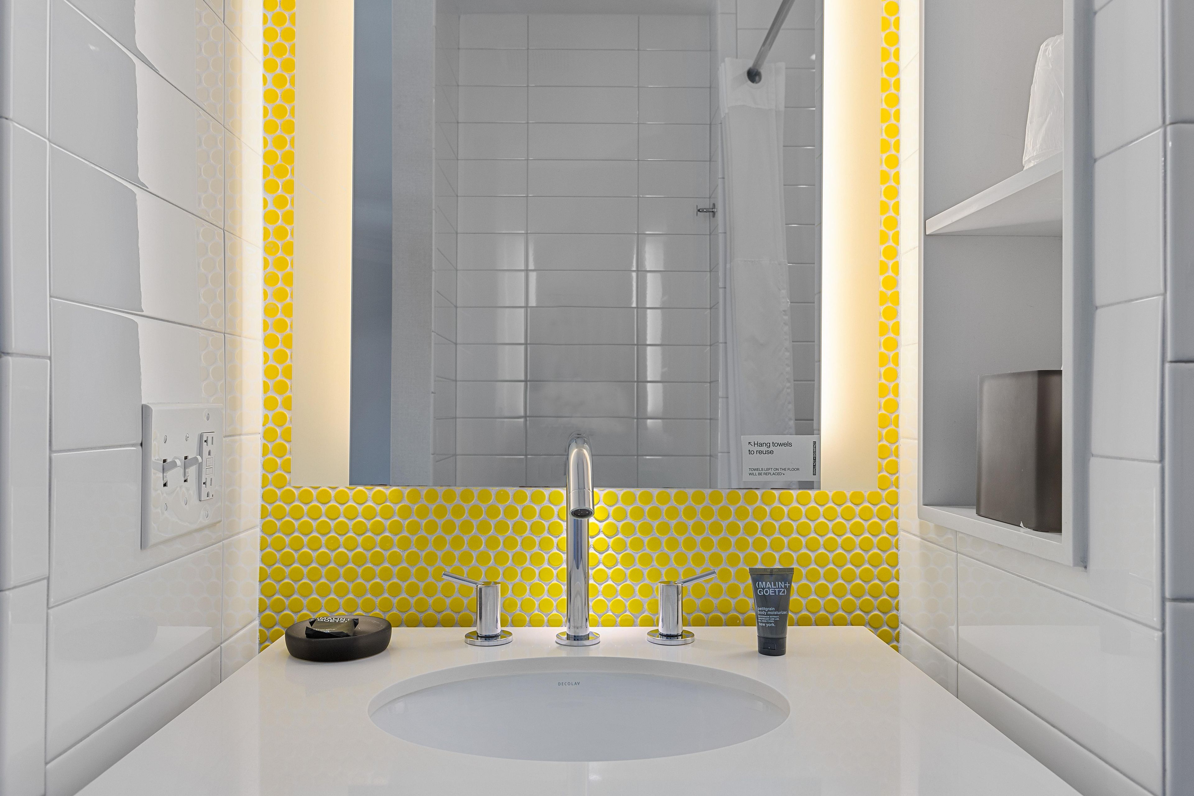 A bathroom with a white sink, a mirror, and yellow patterned tiles.