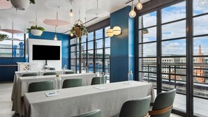 A modern conference room with large windows, a flat-screen TV, and a city view. - Motto by Hilton Washington DC Downtown (Washington)