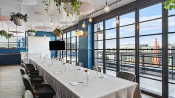 Ein Konferenzraum mit einem langen Tisch, Stühlen und Blick auf die Stadt durch große Fenster.