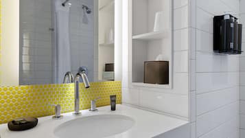 A modern bathroom with a white sink, chrome faucets, a yellow and white tiled backsplash, and a mirror.
