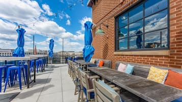 An outdoor patio with tables and chairs, a brick building, and a clear sky.