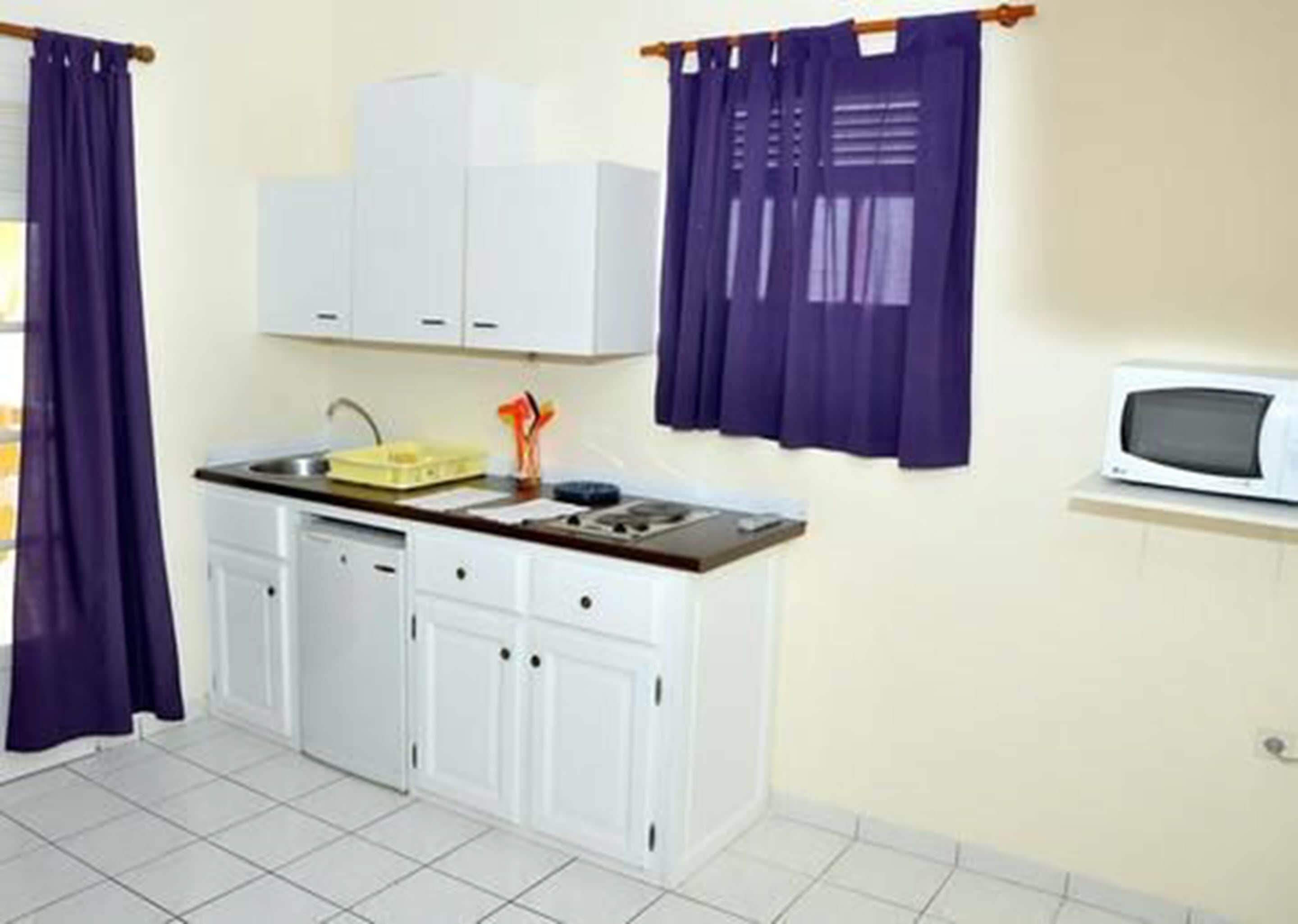 A compact kitchen with white cabinets, a sink, and a microwave.
