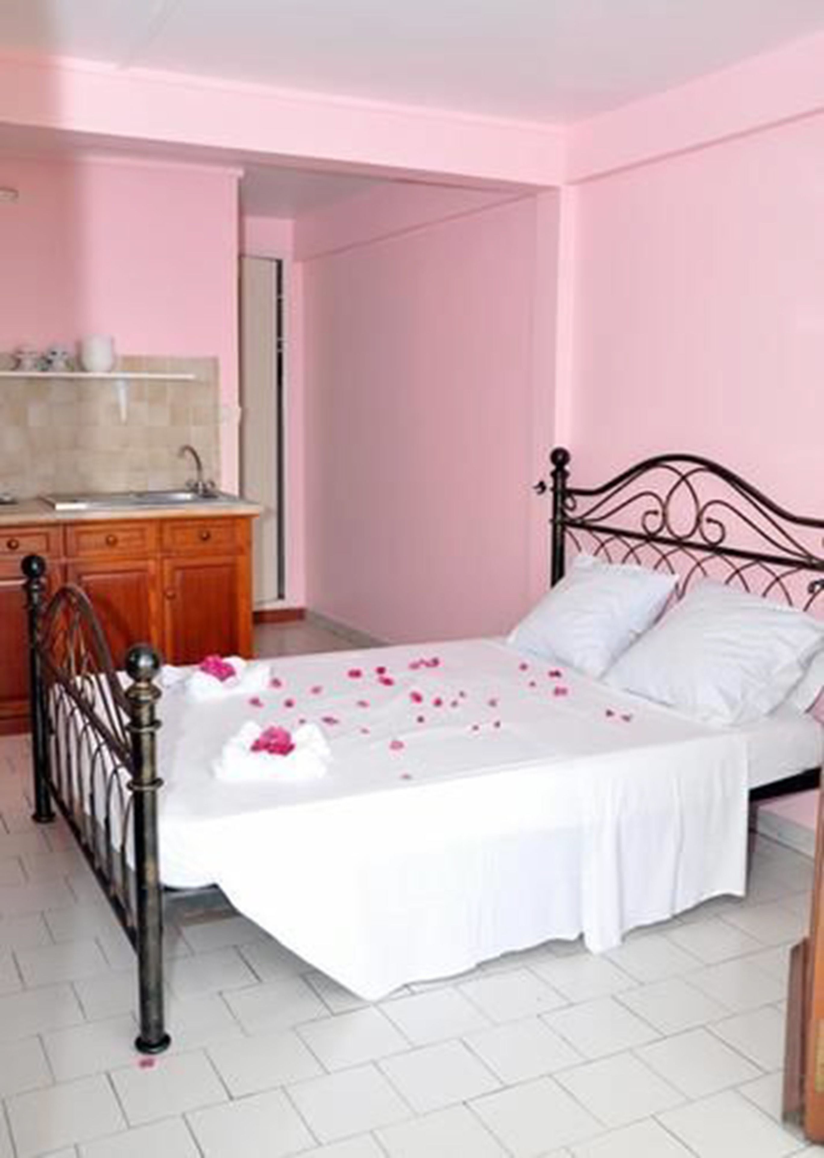 Un dormitorio con una cama, un aparador de madera y un baño visible a través de una puerta abierta.