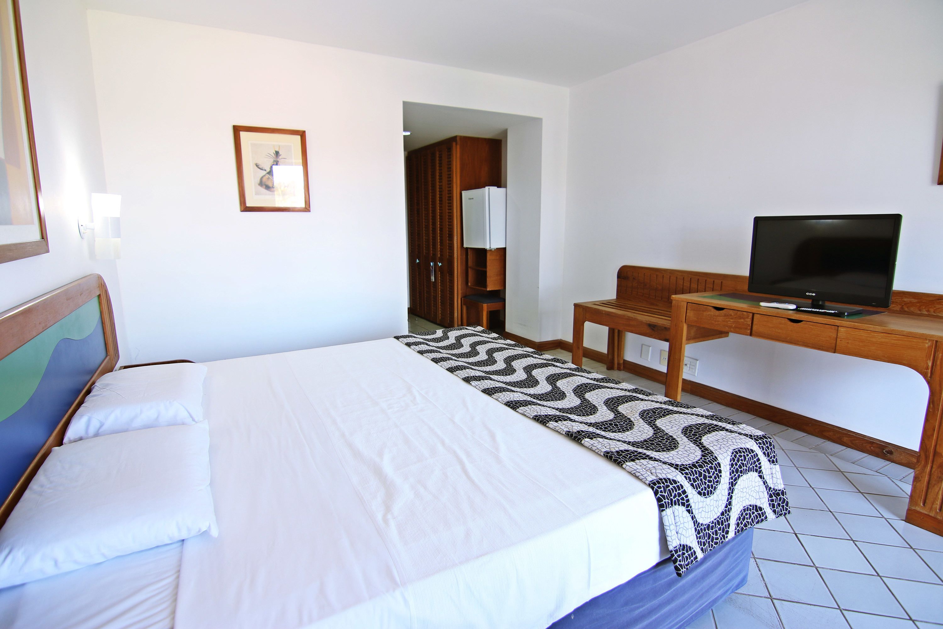 A hotel room with a bed, a desk, a television, and a wardrobe.