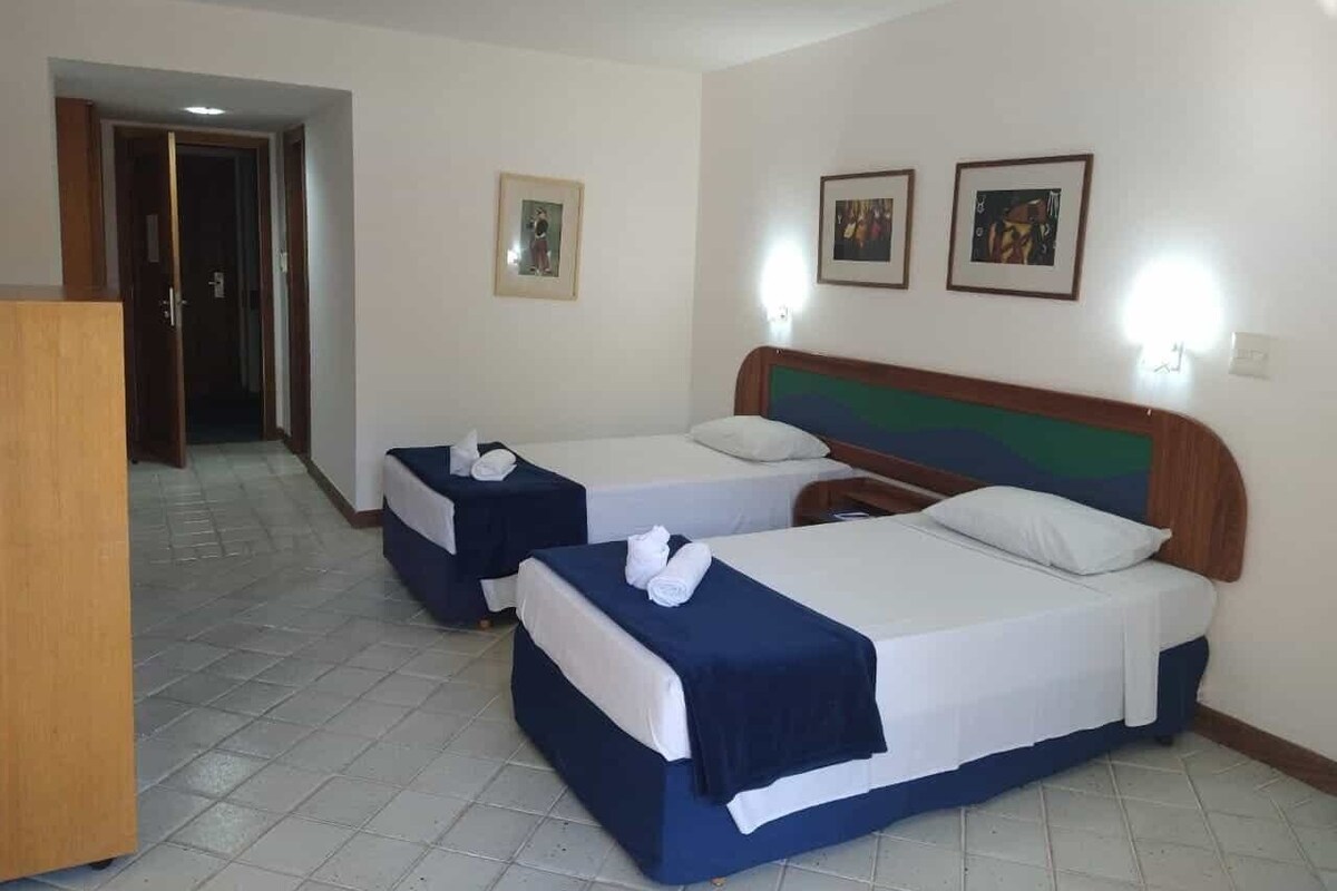 A hotel room with two beds, a wooden headboard, and a desk.