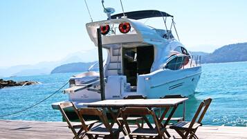 Un barco amarrado en un muelle, con una mesa y sillas al frente.