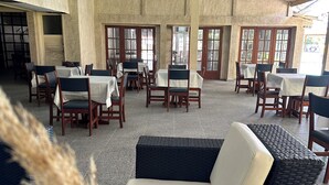 Un espacio al aire libre para comer con mesas y sillas, un sofá de mimbre y vistas a la calle.