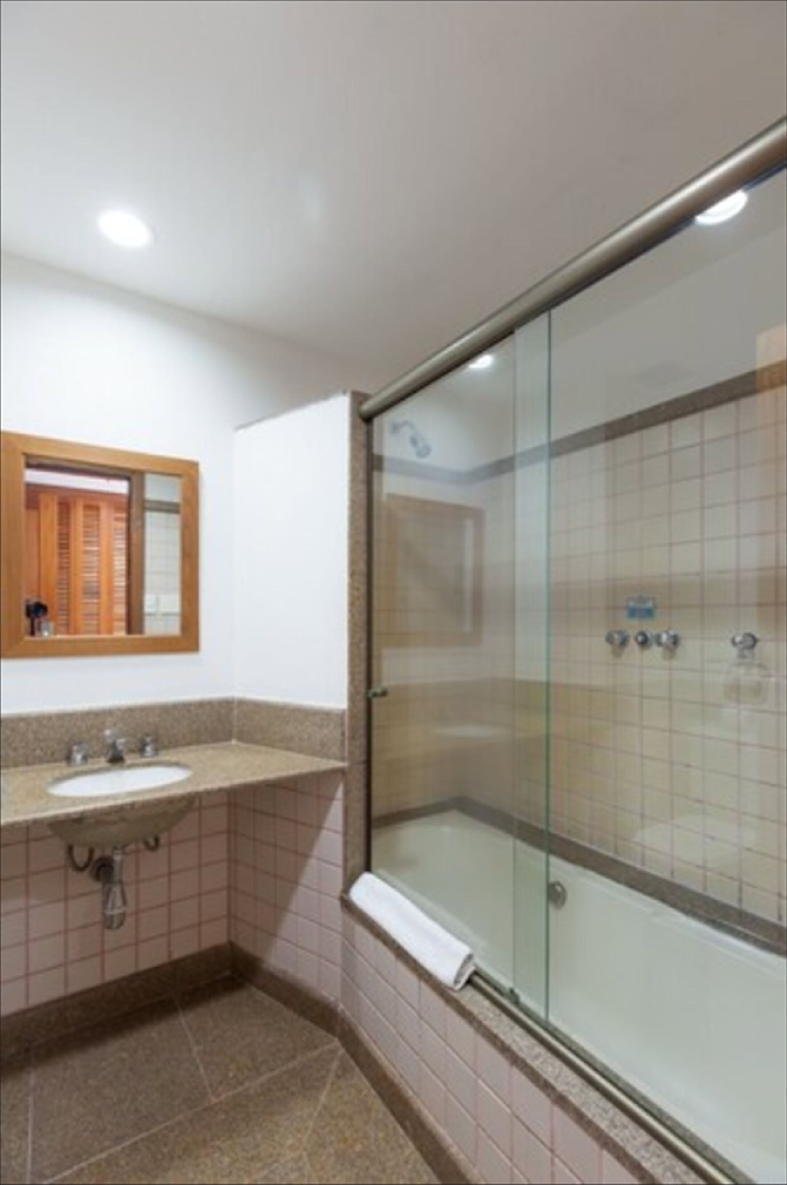 A bathroom with a sink, mirror, and glass-enclosed shower.
