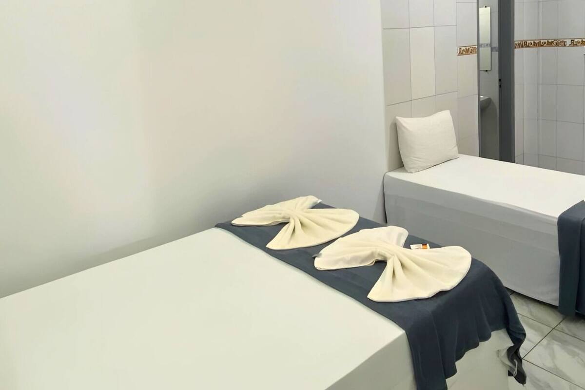 Ein sauberes, modernes Zimmer mit zwei Betten, jeweils mit Kissen und Handtuch.