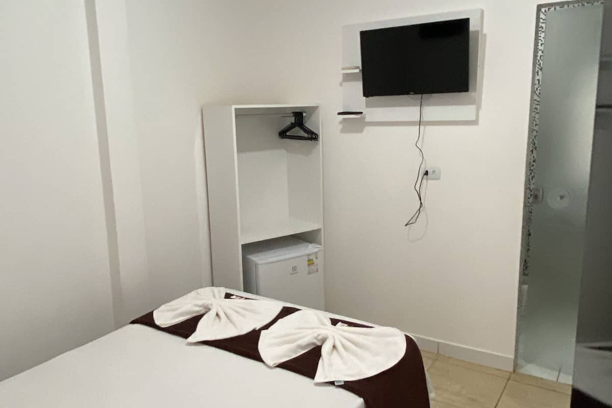 Ein Hotelzimmer mit Bett, Wandfernseher, Kleiderschrank und Spiegel.