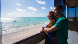 A couple standing by a balcony overlooking a beach with boats and clear skies. - Pousada Vela Mar (Maragogi)