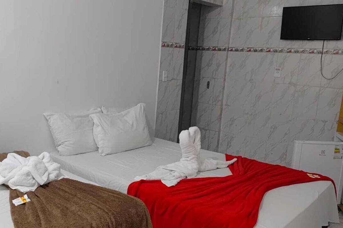 Ein Hotelzimmer mit einem Bett, einem an der Wand montierten Fernseher und einem kleinen Kühlschrank.
