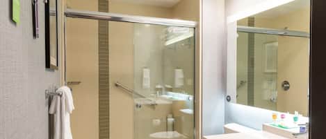 A modern bathroom with a glass-enclosed shower, a white sink, and a large mirror.
