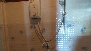 Ett litet badrum med en toalett, en dusch och en hållare för toalettpapper.