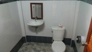 Un baño pequeño con un lavamanos blanco, un inodoro y un espejo sobre el lavamanos.