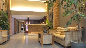A lobby with wicker furniture, a potted plant, and a reception desk.