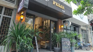 A restaurant named 'FELIZ Hostel' with a modern facade, large potted plants, and a visible menu board outside.