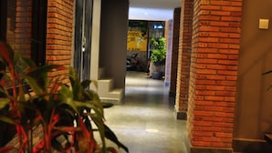 A hallway with brick walls, a tiled floor, and potted plants.