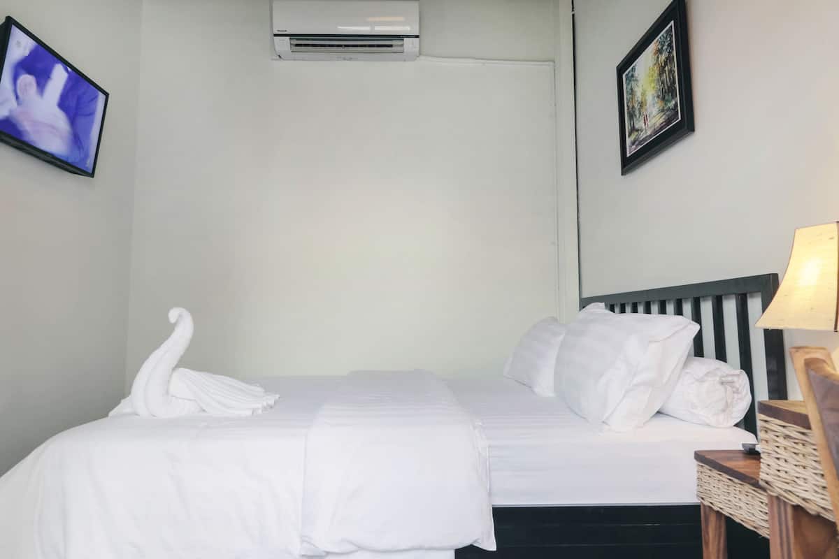Quarto de hotel com cama, ar-condicionado na parede, televisão e quadro emoldurado.