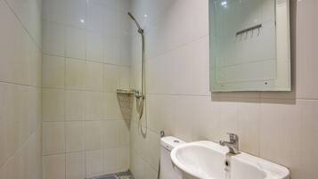 Un baño pequeño con inodoro, lavamanos y ducha.