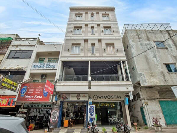 Un edificio de varios pisos con diversas tiendas en la planta baja, incluyendo una tienda de relojes y una joyería.
