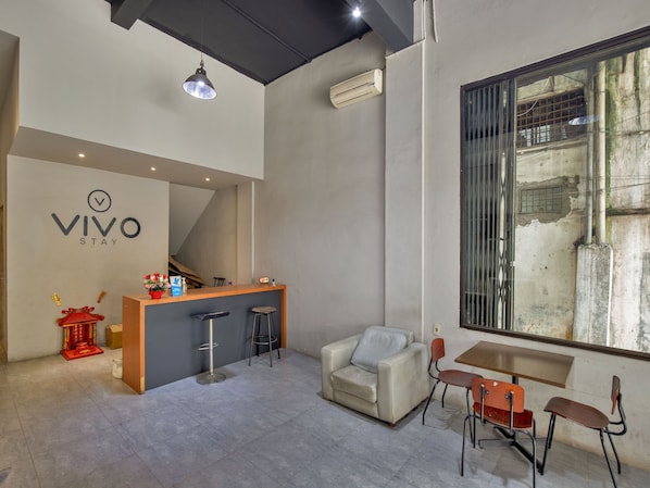 Un moderno vestíbulo de hotel con una recepción, un sofá, un comedor y una escalera.
