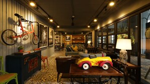 A cozy room with a sofa, a dining table, and a bicycle hanging on the wall. - Nandha Hotel (Bangkok)
