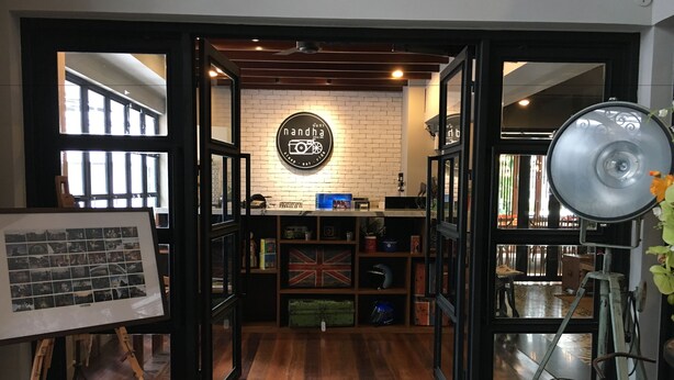 A cozy interior with a brick wall, a framed photo display, and a British flag on shelves. - Nandha Hotel (Bangkok)