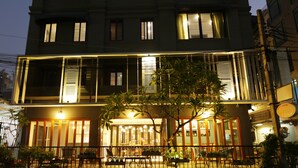 A multi-story building with a ground-level restaurant featuring outdoor seating. - Nandha Hotel (Bangkok)