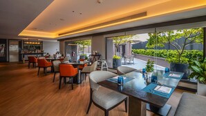 A modern dining area with a long table, multiple chairs, and a bar area in the background. - Marriott Executive Apartments Bangkok, Sukhumvit 50 (Bangkok)