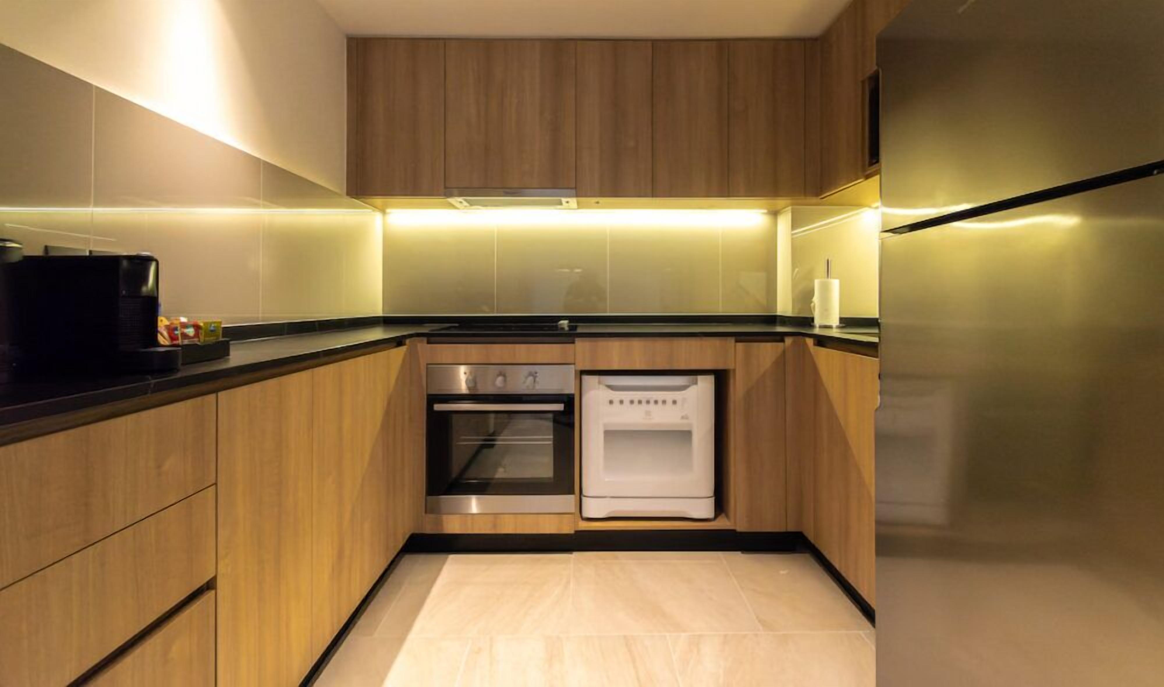 A modern kitchen with wooden cabinets, a built-in oven, a refrigerator, and a microwave.