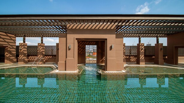 A swimming pool with a tiled floor and a covered walkway. - Marriott Executive Apartments Bangkok, Sukhumvit 50 (Bangkok)