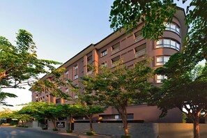 A multi-story hotel with a modern design, featuring balconies on each floor, surrounded by trees and a clear sky. - Marriott Executive Apartments Bangkok, Sukhumvit 50 (Bangkok)