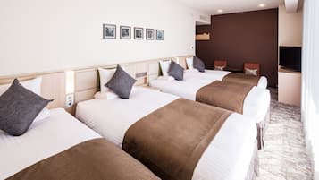 A hotel room with four beds, a desk, and a television.