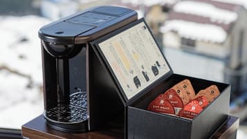 A coffee machine with a manual on the side and a box of coffee pods on a wooden table.