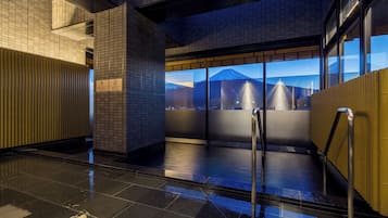 A modern indoor area with tiled walls, a glass elevator, and a view of a mountain.