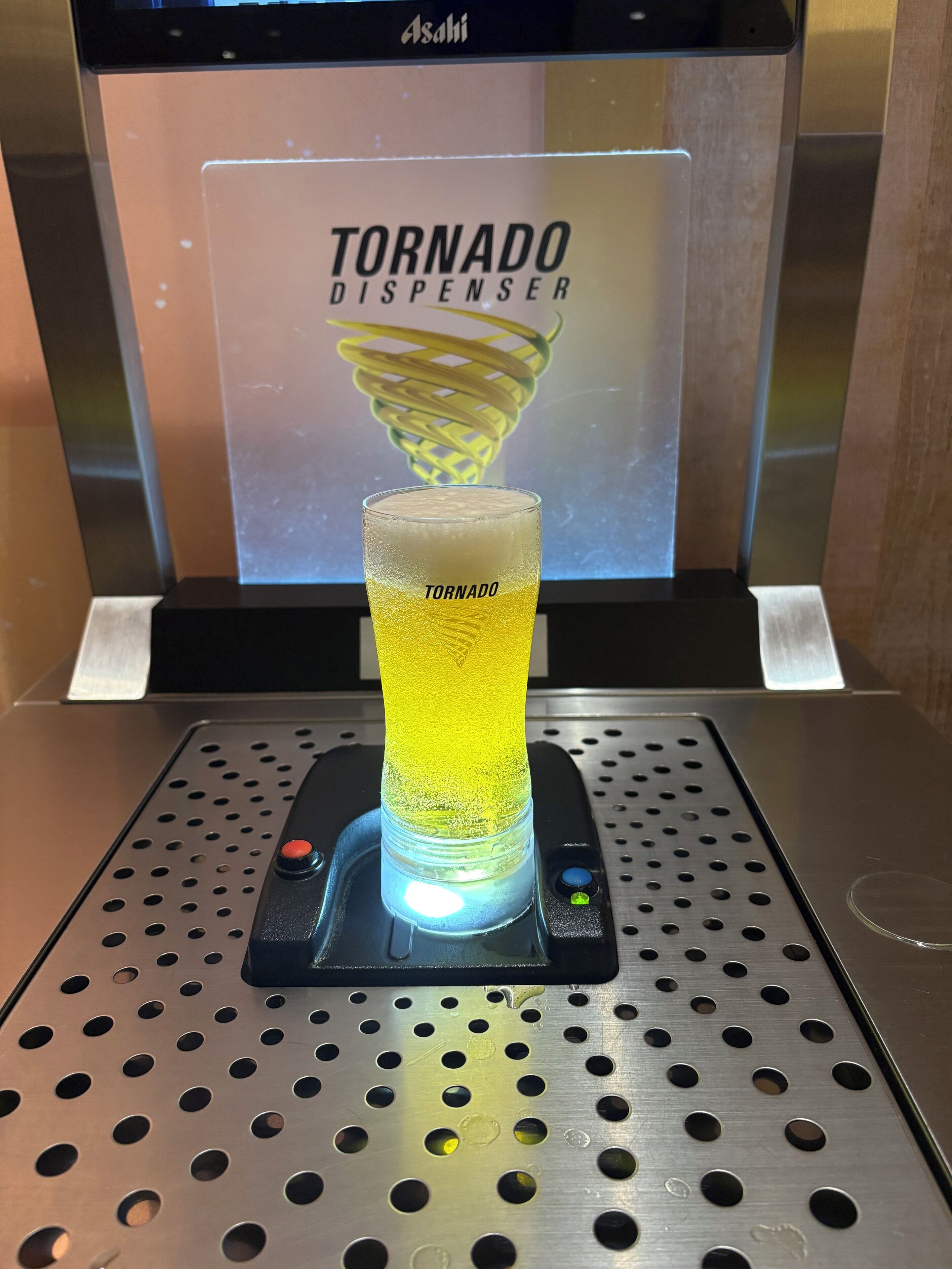 A beer dispenser with a glass of beer labeled "TORNADO" in front of a sign that reads "TORNADO DISPENSER".