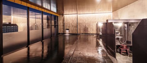 A modern train station with a wet floor, wooden ceiling, and a glass wall on the left.