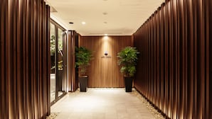 A hallway with wooden paneling, potted plants, and a sign for the Hotel Myataya. - HOTEL MYSTAYS Fuji Onsen Resort (Fujiyoshida)