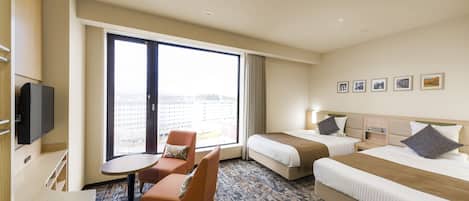 A hotel room with two beds, a desk, a chair, and a large window.