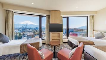 A hotel room with two beds, a TV, and a view of a cityscape with a mountain.