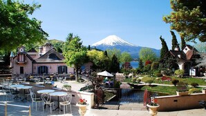 A hotel with outdoor seating, a view of a mountain, and well-maintained gardens. - HOTEL MYSTAYS Fuji Onsen Resort (Fujiyoshida)
