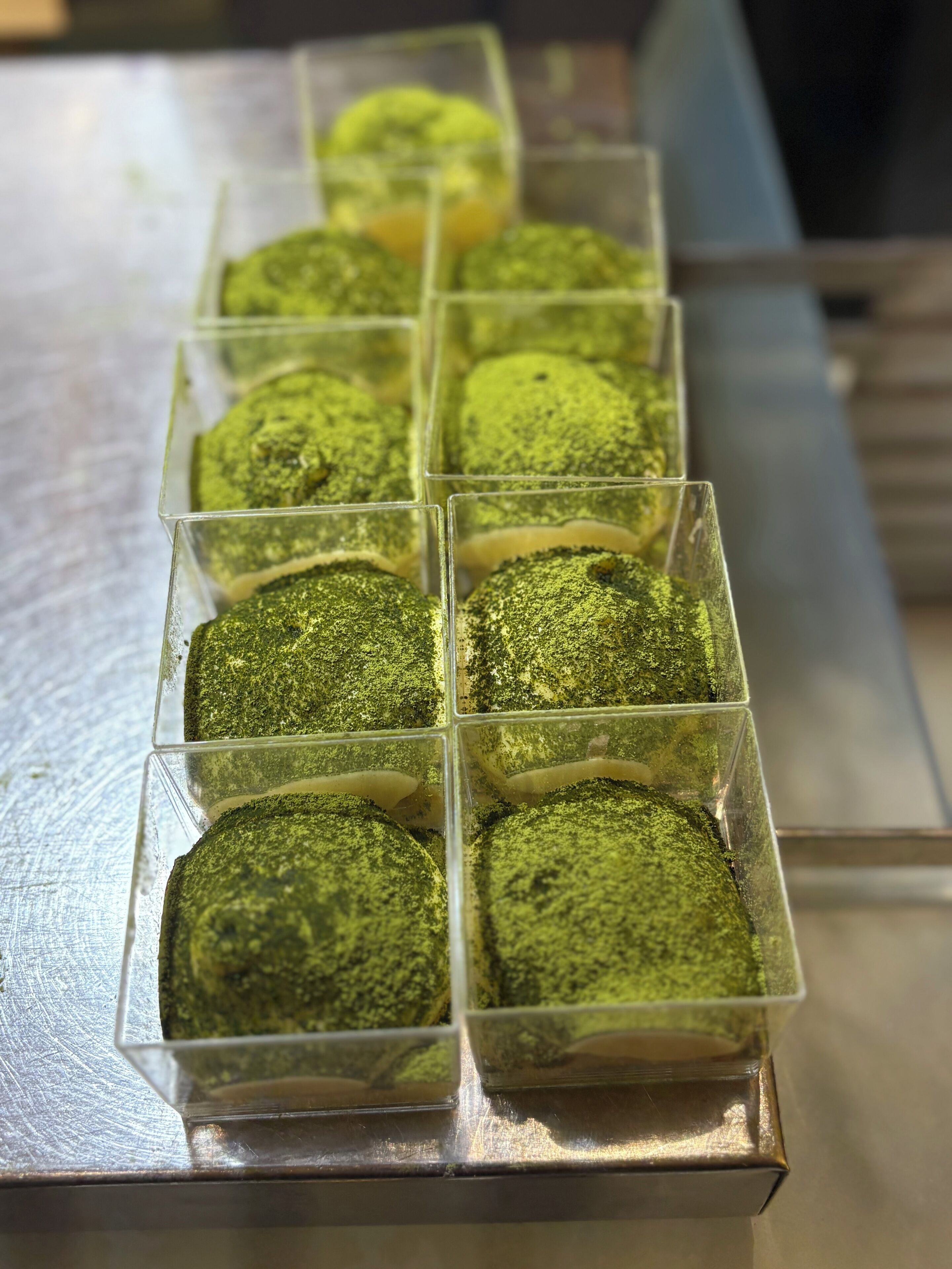 Un plateau de desserts verts présentés dans des récipients transparents.