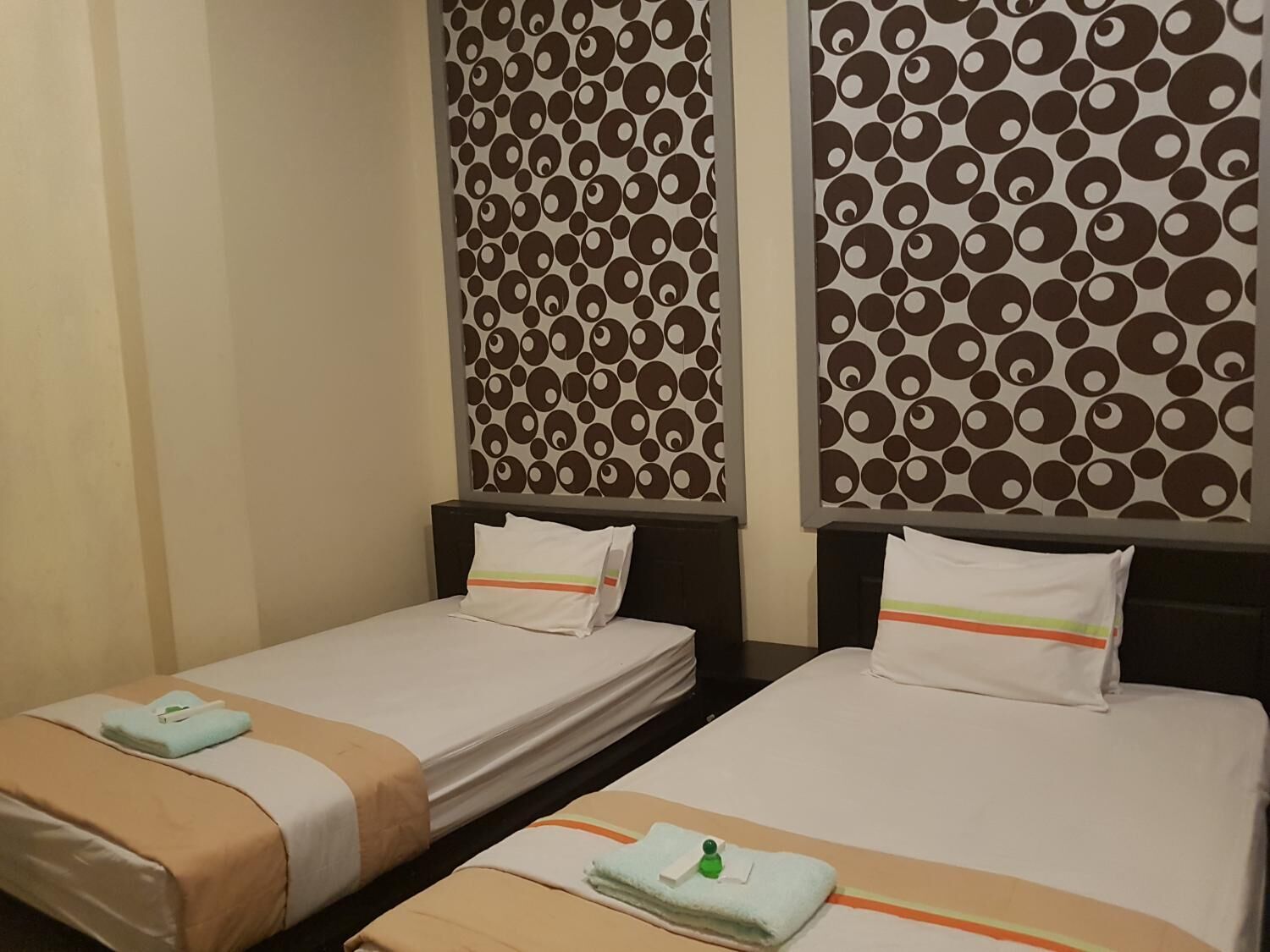 Une chambre d’hôtel avec deux lits simples, chacun étant équipé d’un oreiller et d’une serviette pliée.