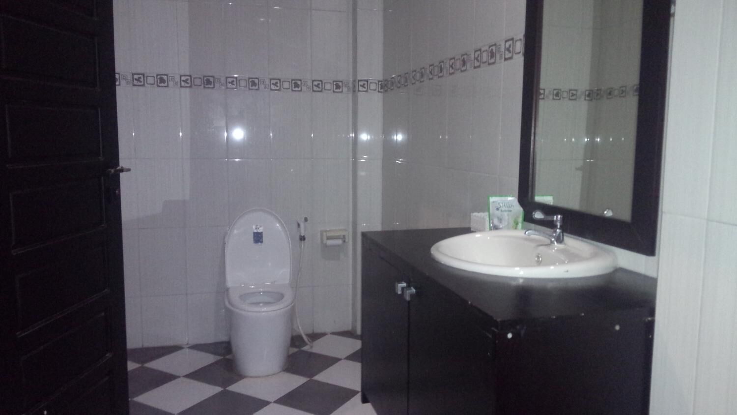 Een badkamer met toilet, wastafel en spiegel.