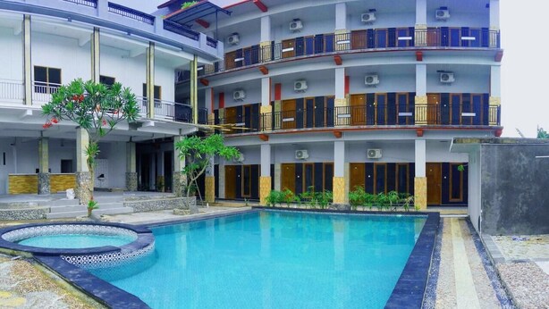 A multi-story hotel with a swimming pool, balconies, and air conditioning units. - Jaya Phita Guest House (Kupang)